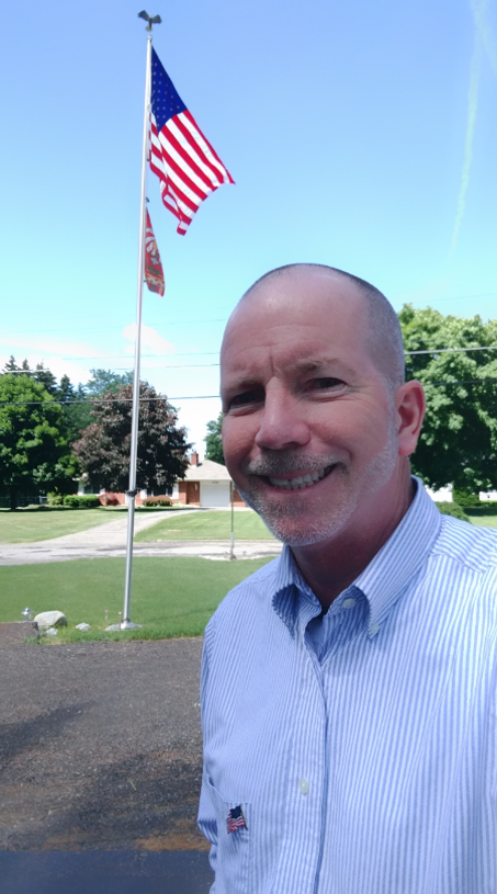 Trustee Tom Klee in front of an American flag